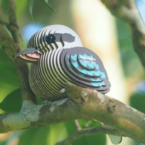 A model kookaburra made of cardboard rests in a tree.